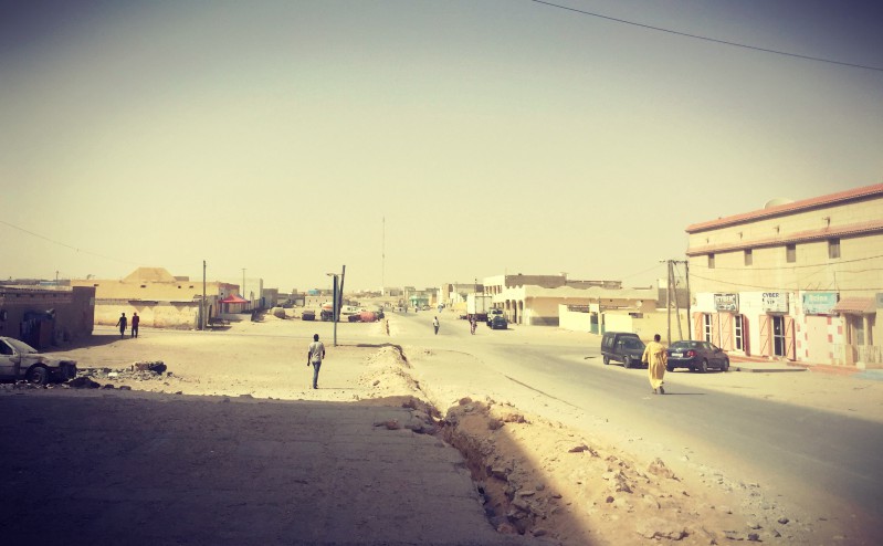 Scène de rue ensablée de Nouadhibou : à droite un homme qui marche, à gauche un garçon et plus loin, deux silhouettes #Off2Africa 14 Nouadhibou Mauritanie © Gilles Denizot 2016