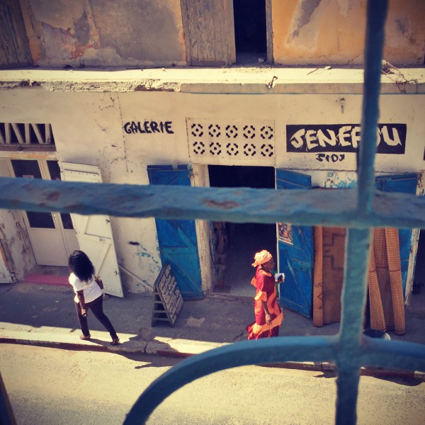 Deux femmes marchent dans la rue, devant la boutique Senefou. L'une en habit traditionnel, l'autre à l'occidentale #Off2Africa 19 Saint-Louis Sénégal © Gilles Denizot 2016