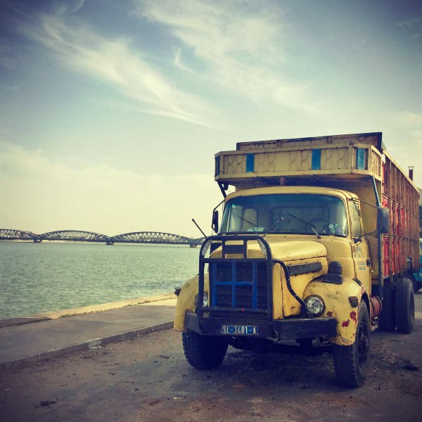 Un camion jaune et rouge au bord du fleuve Sénégal, au loin le pont Faidherbe #Off2Africa 21 Saint-Louis Sénégal © Gilles Denizot 2016