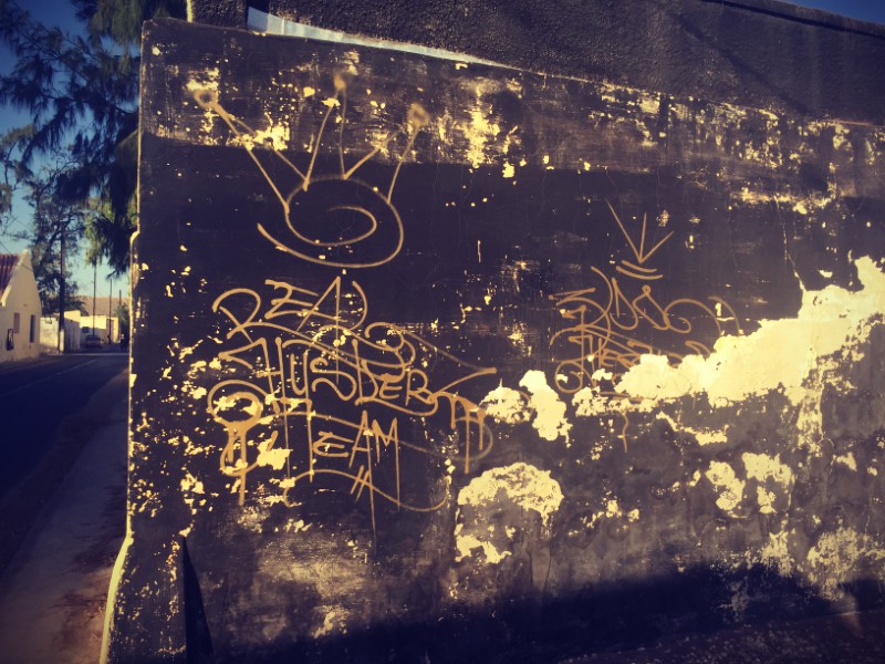 Un mur décrépi marron sur lequel figurent des graffitis #Off2Africa 21 Saint-Louis Sénégal © Gilles Denizot 2016