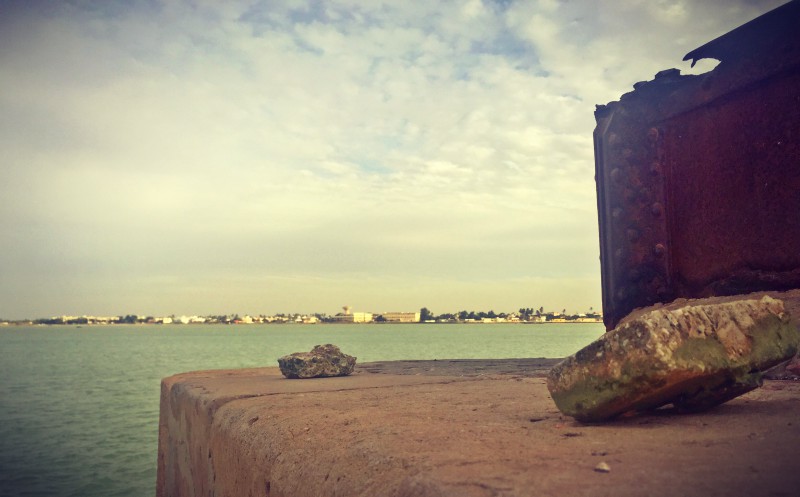 Au bord du fleuve, détail de la grue rouillée et deux pierres qui se sont détachées du mur. Au loin, le fleuve #Off2Africa 21 Saint-Louis Sénégal © Gilles Denizot 2016