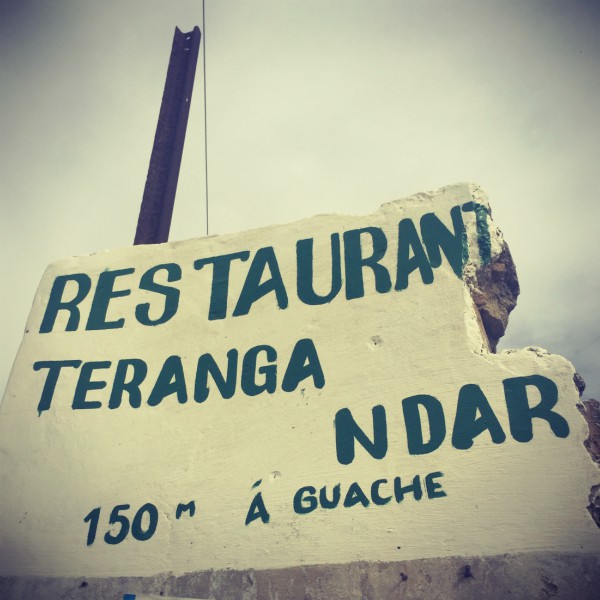 Un mur jaune sur lequel est écrit : Restaurant Teranga Ndar 150 m á guache (sic) #Off2Africa 21 Saint-Louis Sénégal © Gilles Denizot 2016