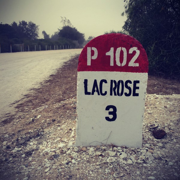 Panneau indicateur P 102 en pierre, il est écrit : lac rose 3 #Off2Africa 30 Lac Retba Sénégal © Gilles Denizot 2016