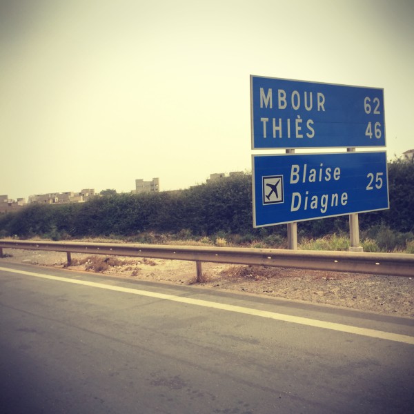 Sur la route, un panneau indique les distances pour Mbour et Thiès #Off2Africa 31 M'bour Sénégal © Gilles Denizot 2016