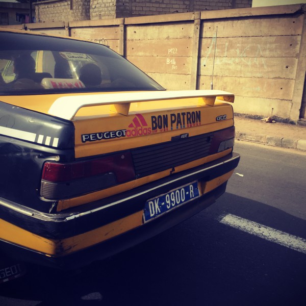 L'arrière d'un taxi Peugeot jaune avec l'inscription Bon Patron #Off2Africa 39 Dakar Sénégal © Gilles Denizot 2017