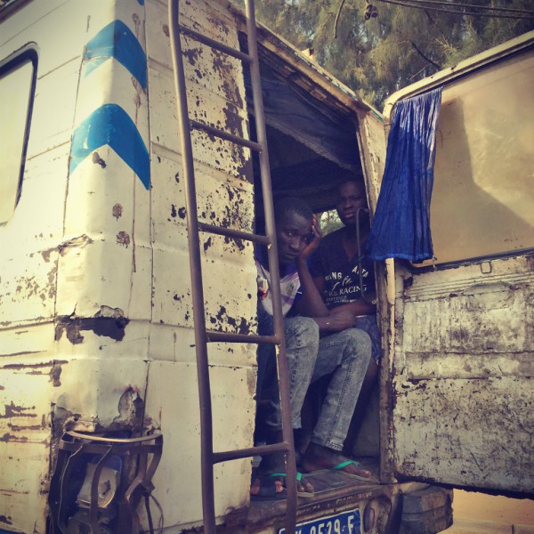 Deux hommes assis à l'arrière d'un minibus regarde à travers la porte arrière ouverte #Off2Africa 35 Dakar Sénégal © Gilles Denizot 2016