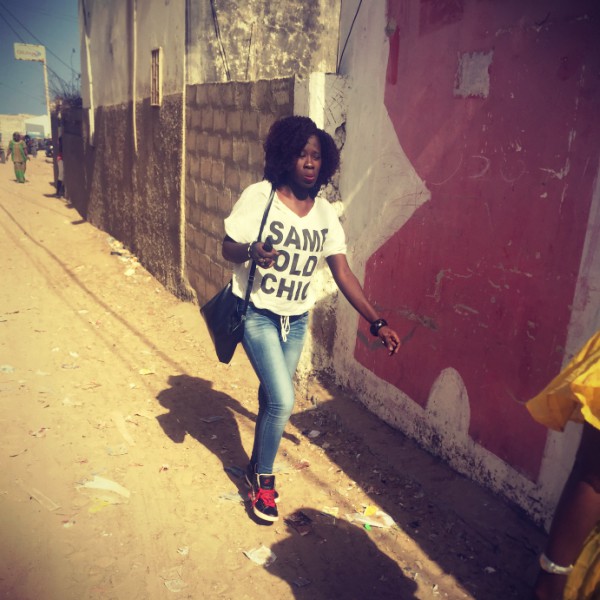 Une femme en baskets, jeans et t-shirt marche dans une rue ensablée de Yoff #Off2Africa 39 Dakar Sénégal © Gilles Denizot 2017