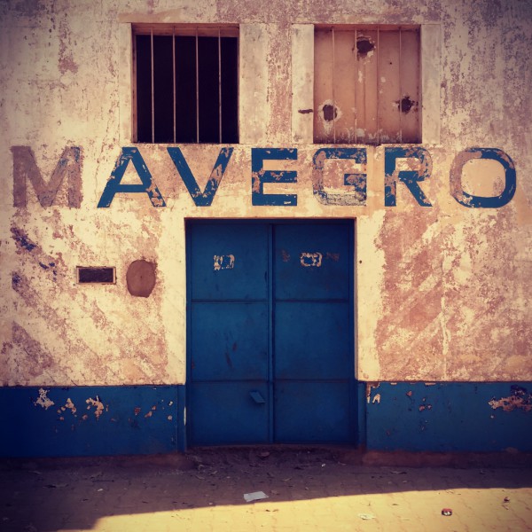 Entrée d'un bâtiment blanc et bleu, inscription délavée Mavegro #Off2África 49 Ziguinchor Bissau © Gilles Denizot 2017