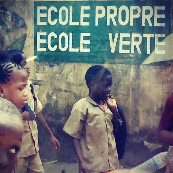 Une inscription ECOLE PROPRE ECOLE VERTE sur un mur de Conakry, des écoliers passant devant #Off2Africa 55 Conakry Guinée © Gilles Denizot 2017