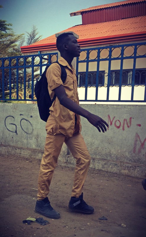 Un étudiant en uniforme marche devant une école #Off2Africa 55 Conakry Guinée © Gilles Denizot 2017