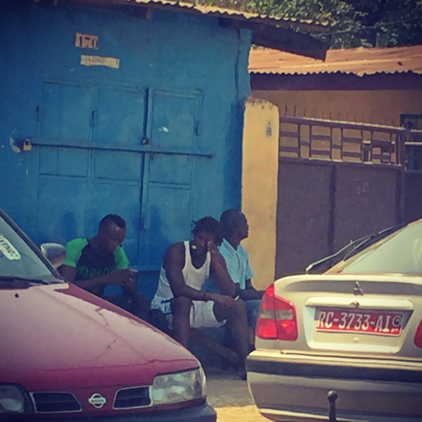 Des hommes assis contre une paroi bleue dans la rue #Off2Africa 54 Conakry Guinée © Gilles Denizot 2017