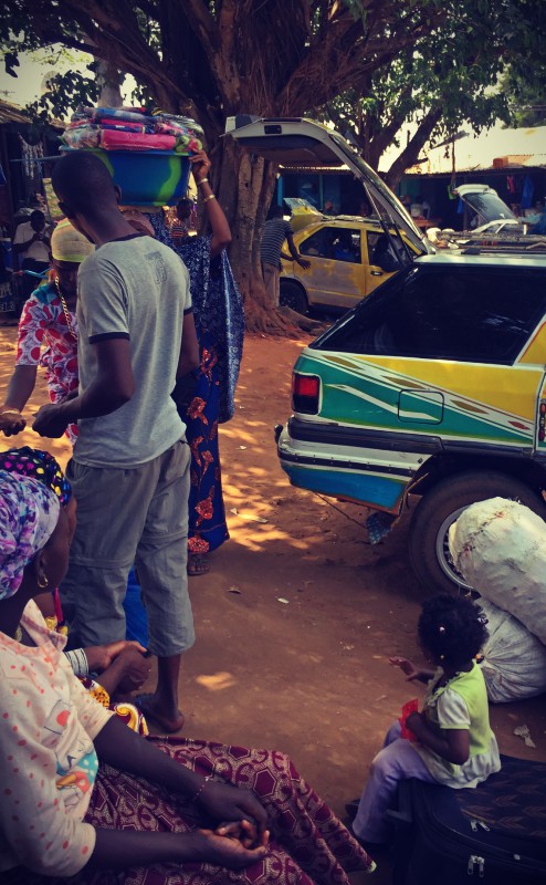 Sous un grand arbre, les taxis-brousses, les femmes, hommes et enfants attendent #Off2Africa 82 Mamou Guinée © Gilles Denizot 2017