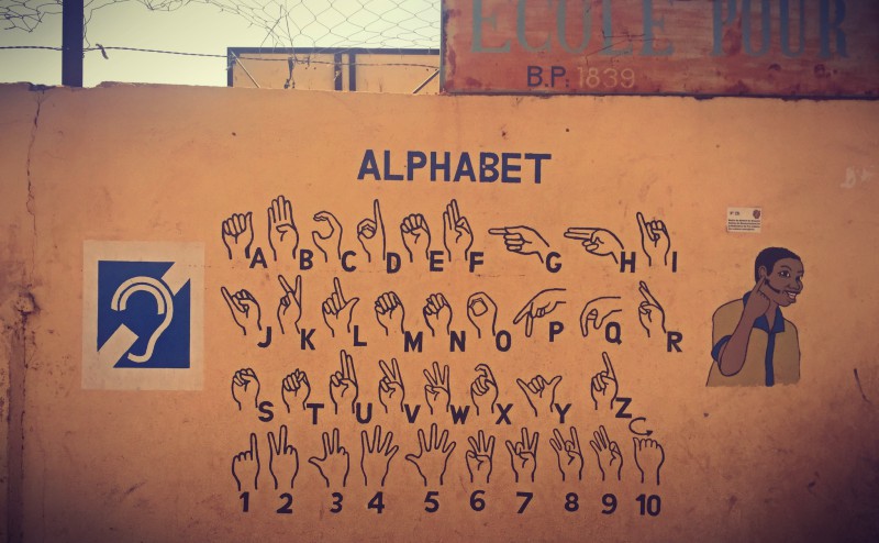 Sur un mur orangé, les lettres et les nombres en langue des signes locale #Off2Africa 88 Sikasso Mali © Gilles Denizot 2017