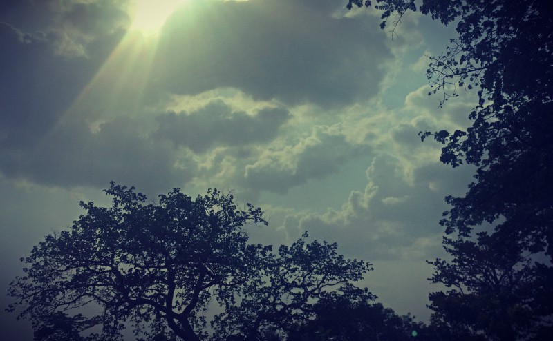 Le soleil filtre à travers les nuages dans le ciel ivoirien, encadré par des arbres #Off2Africa 89 Bouaké Côte d'Ivoire