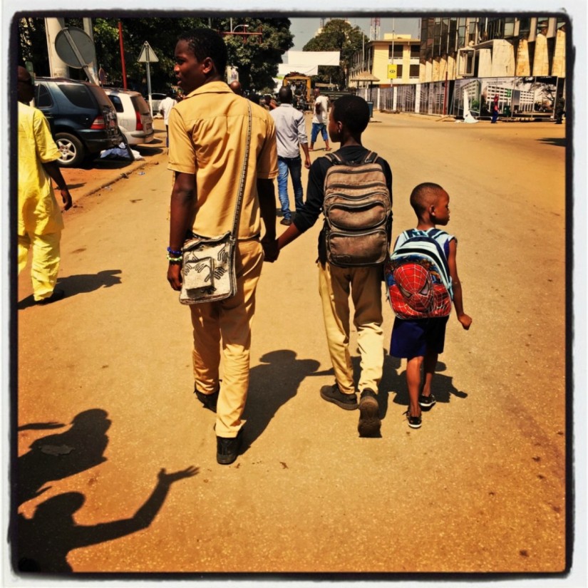 Trois écoliers marchent dans une rue en se tenant la main #Off2Africa 68 Conakry Guinée © Gilles Denizot 2017
