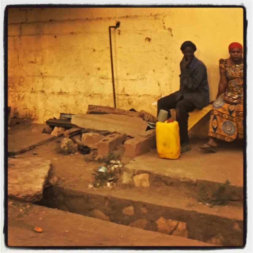 Au bord d'une route à l'entrée de Bamako, un homme et une femme assis sur un banc de pierre. Devant eux un bidon jaune #Off2Africa 84 Kankan Guinée — Bamako Mali © Gilles Denizot 2017