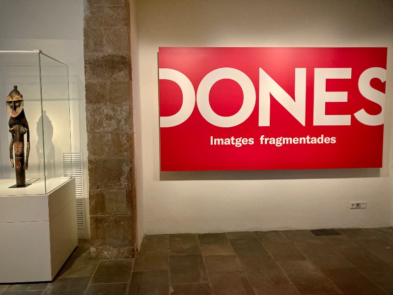 Une affiche rouge sur un mur blanc, à gauche, une statue dans une vitrine en verre © Gilles Denizot 2022