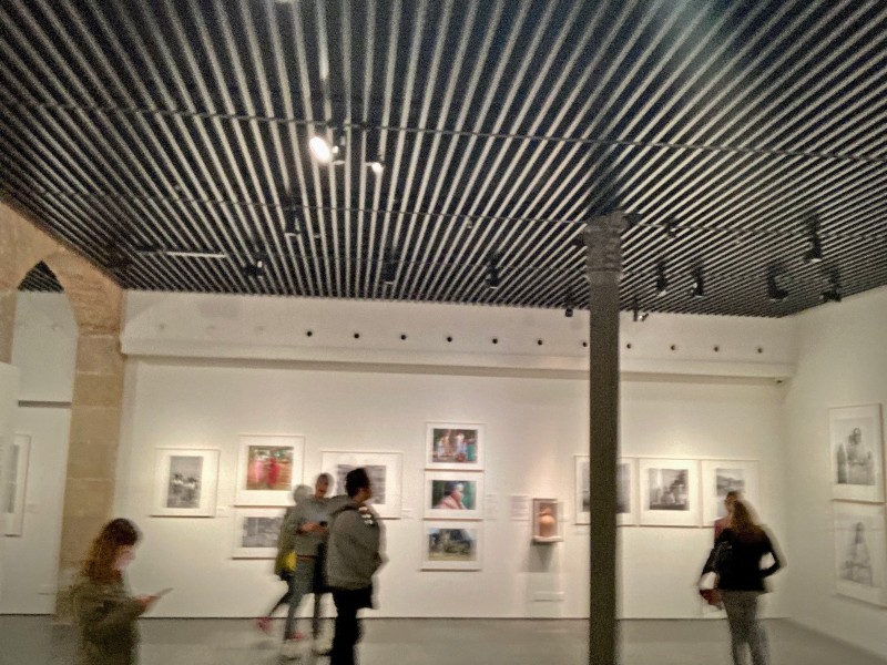 Une salle de musée, des photos accrochées aux murs et des visiteurs en mouvement © Gilles Denizot 2022