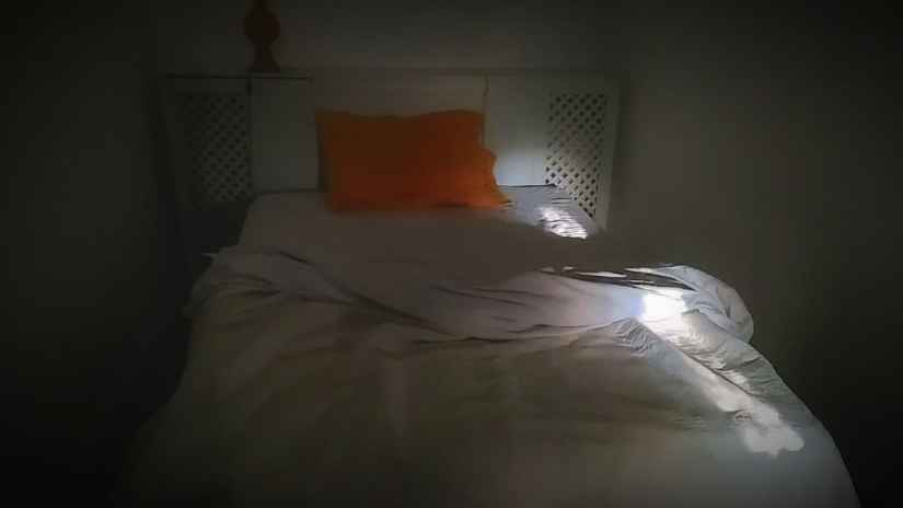 Un rayo de luz cae sobre una cama toda blanca, con almohada naranja #InAfrica Carcajada © Gilles Denizot 2017