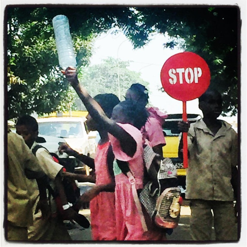 Un garçon tient un panneau STOP laissant passer des écoliers dans une rue de Conakry #Off2Africa 55 Conakry Guinée © Gilles Denizot 2017