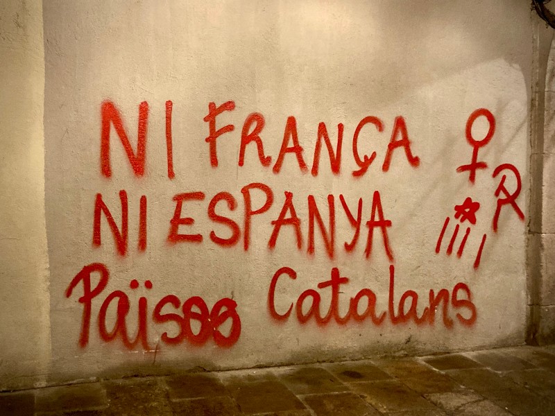 Sur un mur beige, un graffiti en lettres rouges dit NI FRANÇA NI ESPANYA P