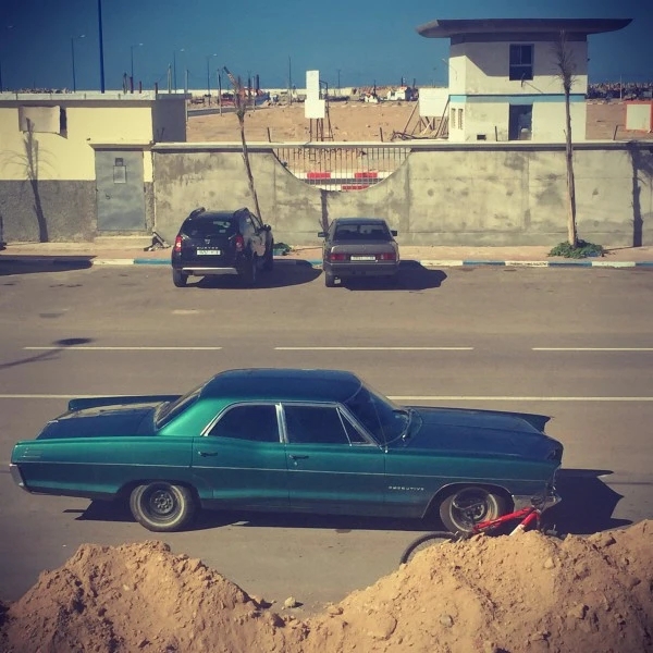 Une voiture verte (américaine ?) devant un tas de sable #Off2Africa 10 Tarfaya Maroc © Gilles Denizot 2016