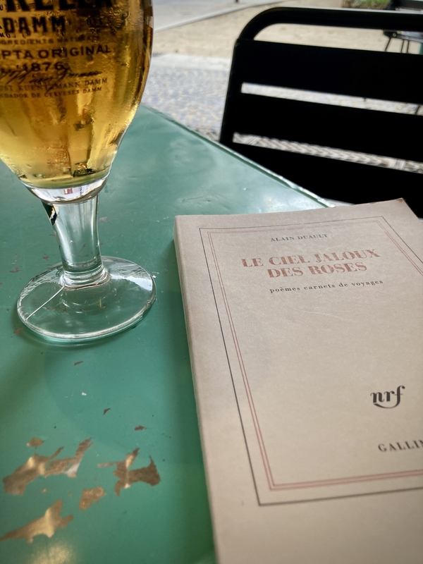 Une bière et un livre posés sur une table turquoise