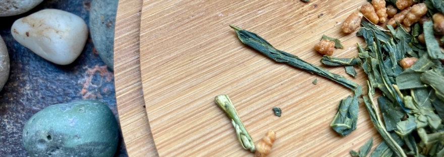 Des galets, une planche en bois avec des feuilles de thé vert et des grains de riz grillé © Gilles Denizot 2023