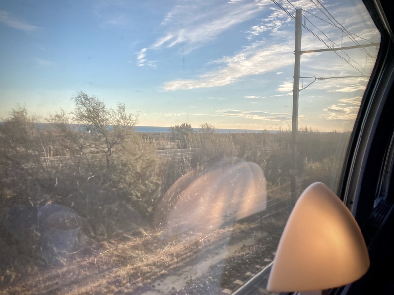 Vitre du train, voie de chemin de fer, pylône électrique et l'eau au loin #Off2Europe Resfeber Stress © Gilles Denizot 2023