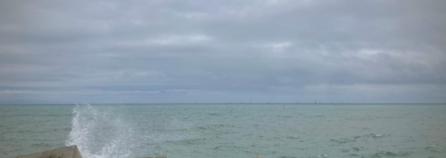 L'horizon de la mer à Barcelone, ciel couvert, eau vert-de-gris, vagues qui s'écrasent contre les blocs de bétons tagués ©GD24 #Vaste silence